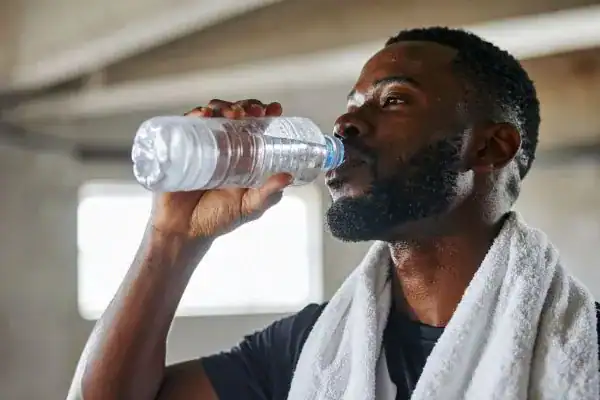 Image of man drinking water to improve hydration  after work out.